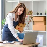 Beautiful young Asian business owner woman prepare parcel box and check online orders of product for deliver to customer. Shopping Online concept.